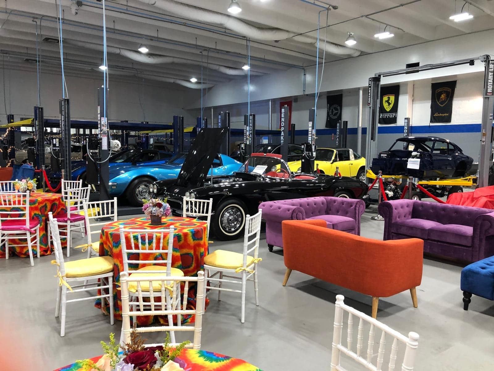 An evening on the garage floor · The cars behind the ropes, tables set among the lifts